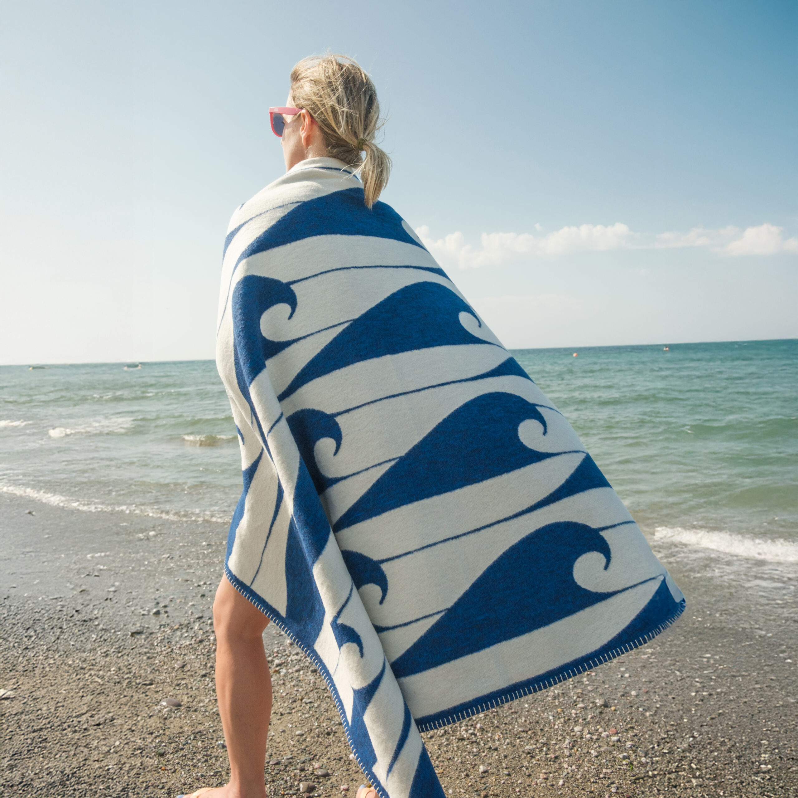 Ethically made Daymer Blue throw blanket on a beach