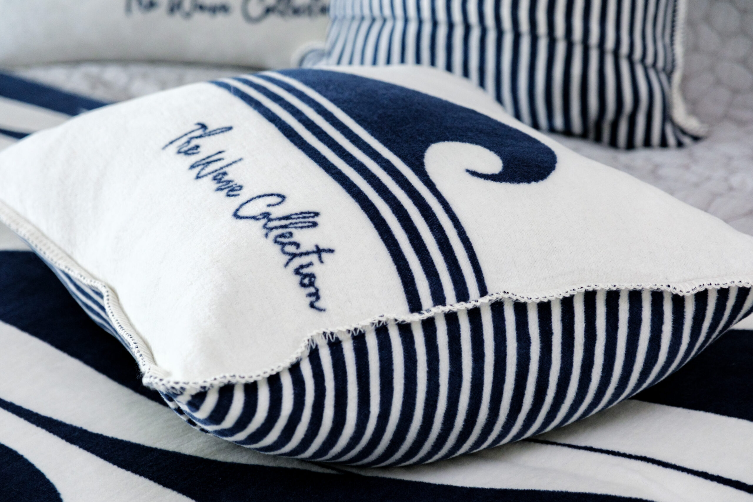 Reversible coastal cushion styled on a sofa or bed in a contemporary interior setting